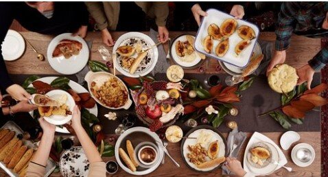 Image of a dinner table filled with food and people filling up their plates.