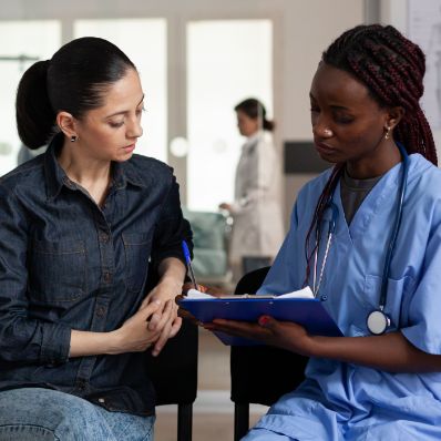 nurse talking to young female patient with clipboard at facility