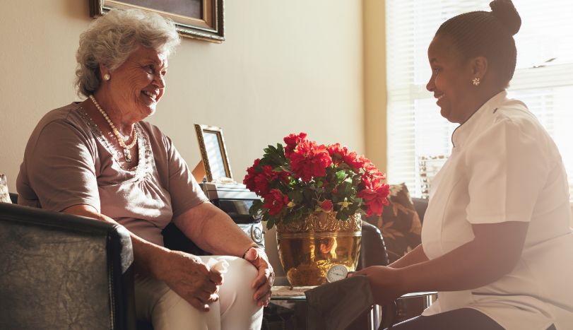 Female hospice nurse visiting senior patient for checkup in patient house
