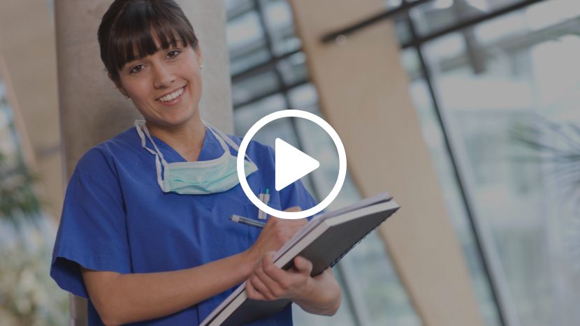 Hospice worker smiling with clipboard and mask at hospice facility