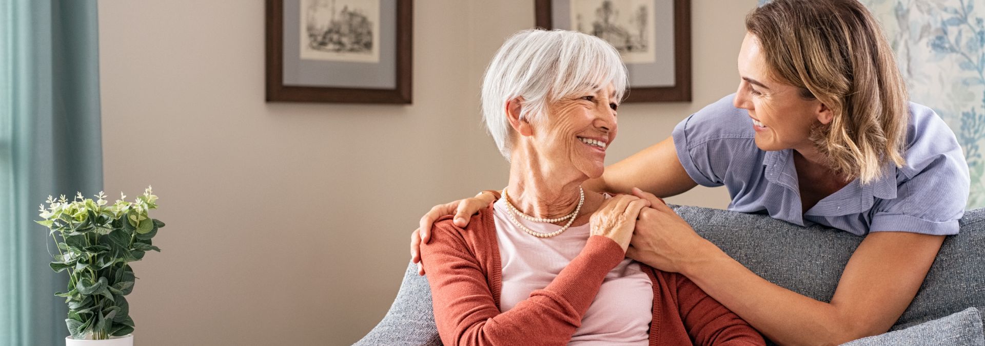 young hospice nurse holding hospice patient on couch at home