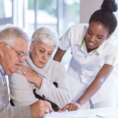 Hospice worker talking to senior woman and senior man about hospice care at hospice facility