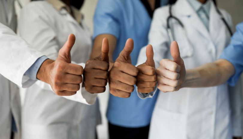 Four nurses doing thumbs up movement with one hand each