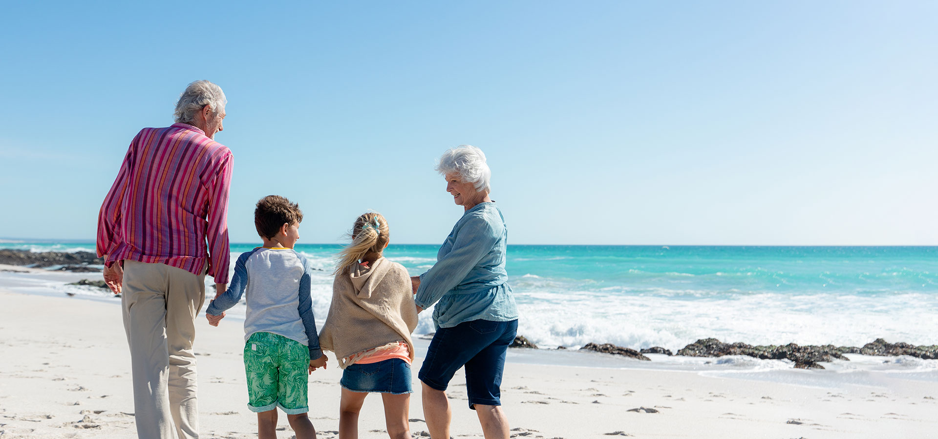 Grandparents and their grandchildren walking on los angeles beach during daytime