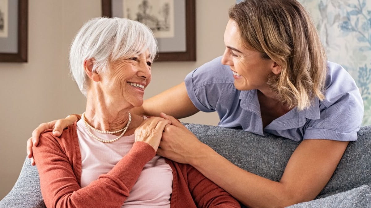 young hospice nurse holding hospice patient on couch at home