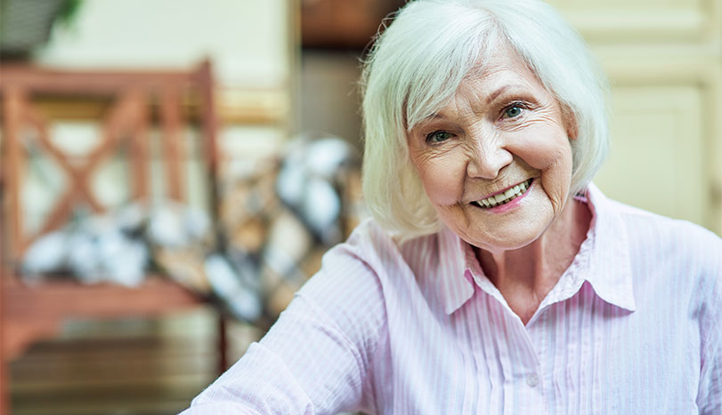 Elderly woman smiling with pink shirt and short hair