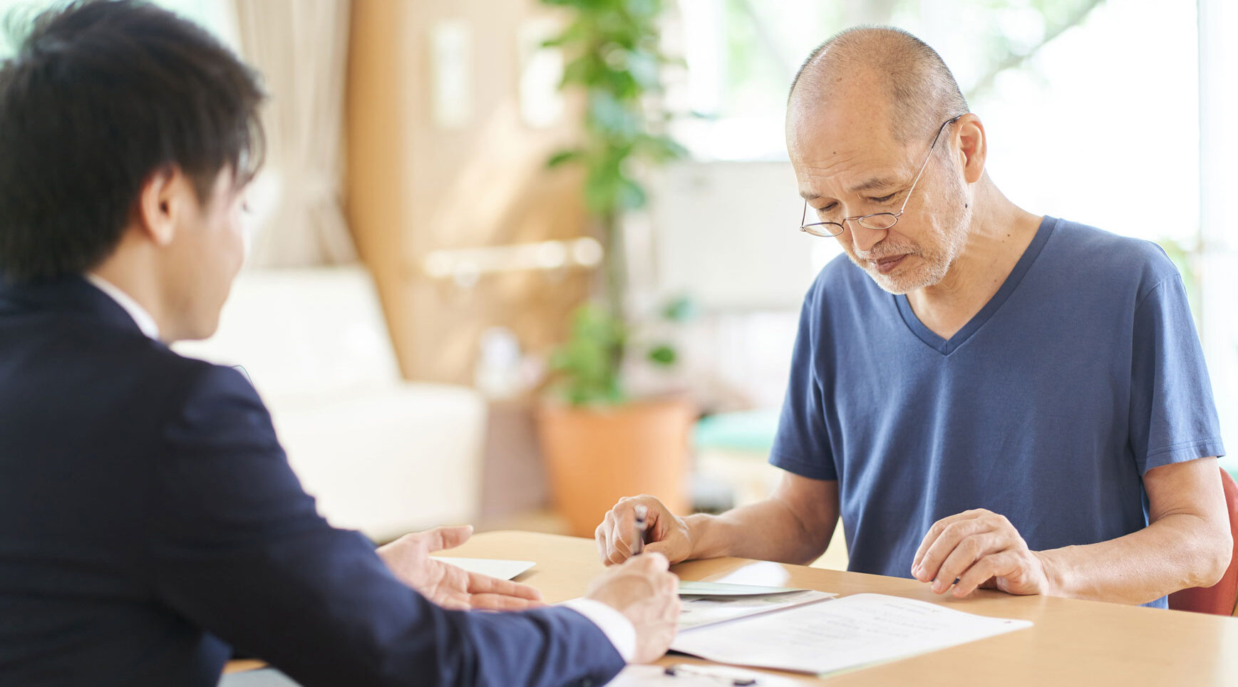 An elderly gentleman signing papers in front of a legal counsel