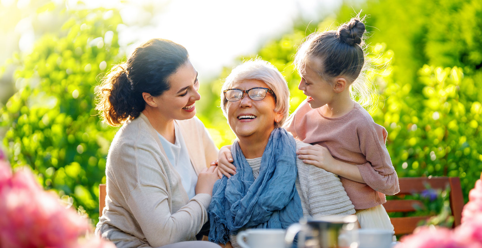 Una mujer y una niña sonriendo y riendo con un anciano al aire libre